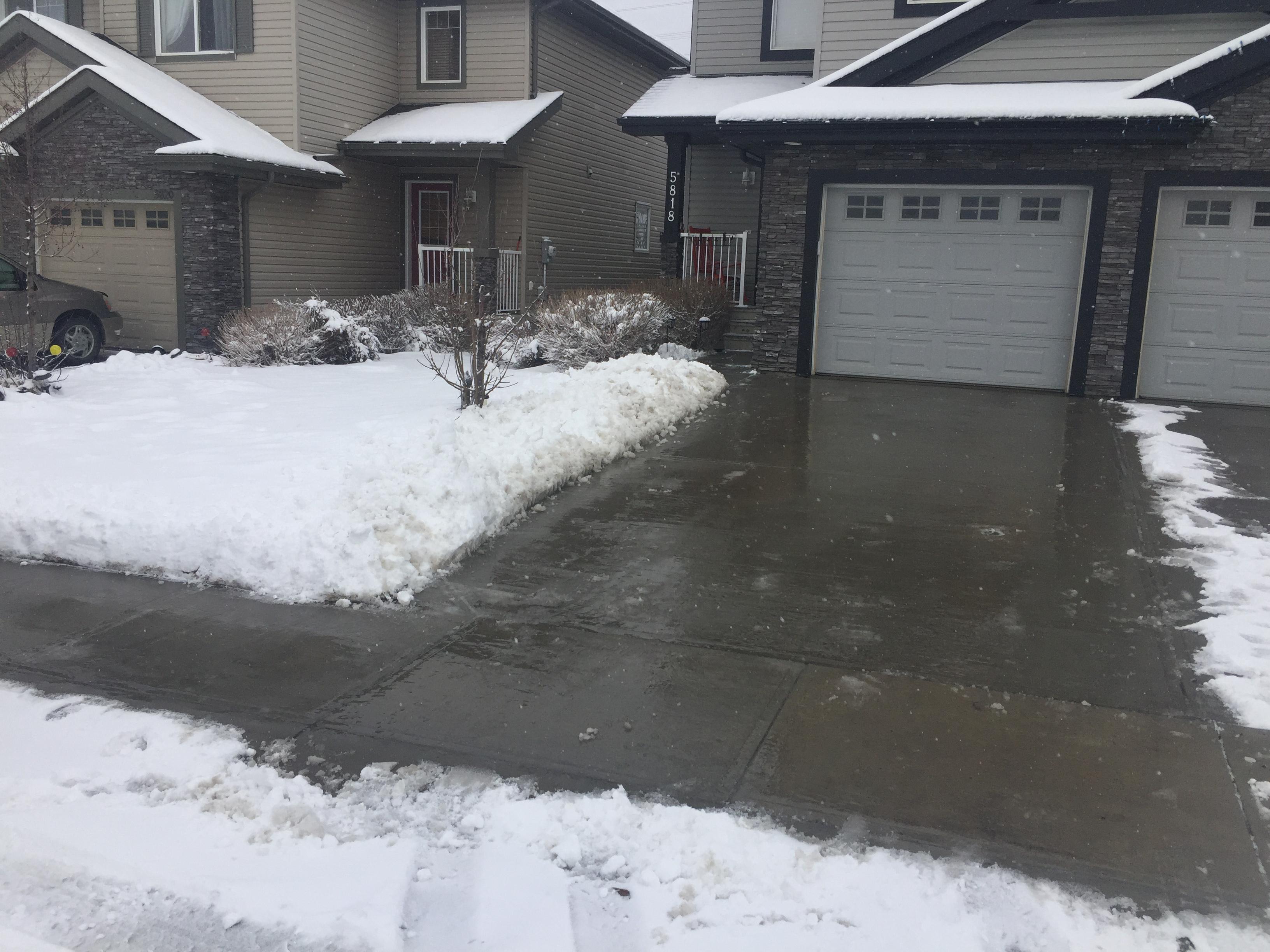 Residential driveway cleared of snow with snow pushed to sides